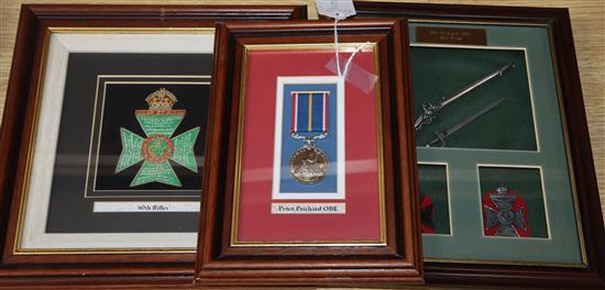 A framed OBE and military badges